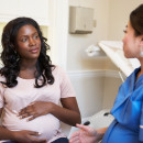 Pregnant Woman Meeting With Nurse In Clinic